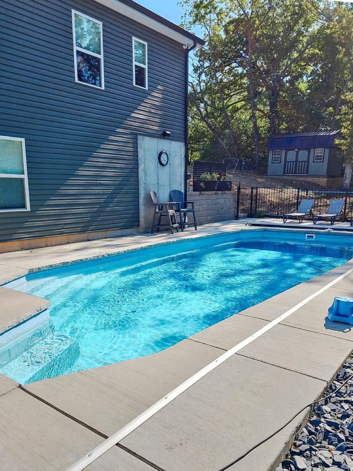 Clean residential swimming pool with lounge chairs cared for by Blue Anchor in Florissant, MO